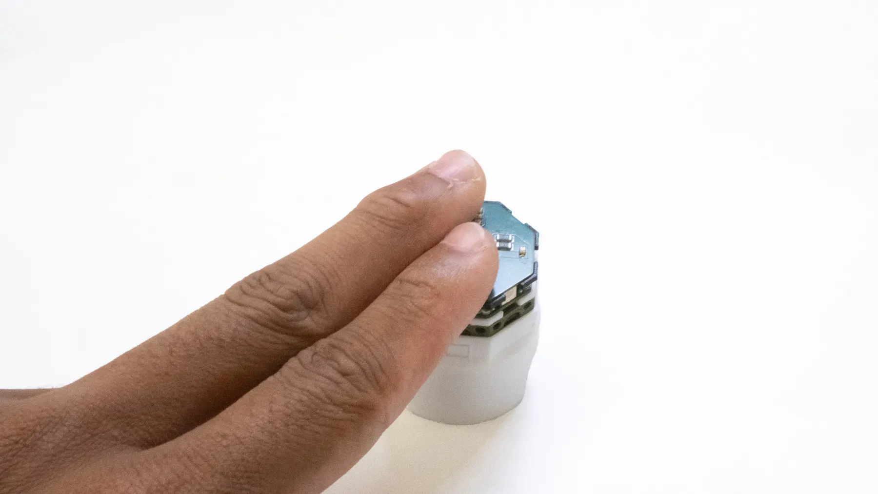 A finger tapping the top of one robot.